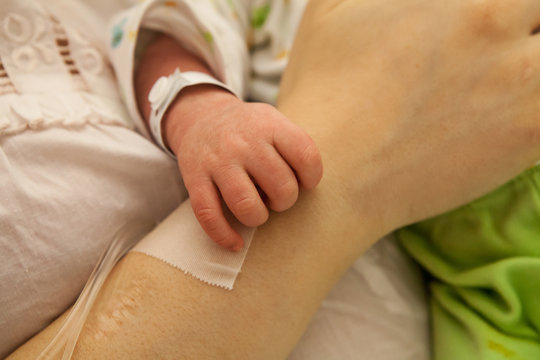 Mano di neonato che poggia sul braccio della mamma