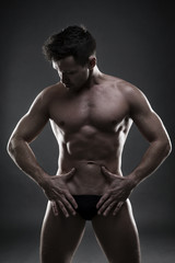 Obraz na płótnie Canvas Handsome muscular bodybuilder posing on gray background. Low key studio shot