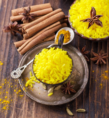 Bright yellow boiled rice with turmeric and aromatic spices on a dark wooden background in old vintage metal bowl