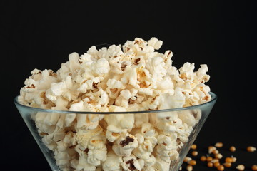 Popcorn in a glass bowl on black background
