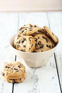 Chocolate chip cookies in bowl on white wooden background