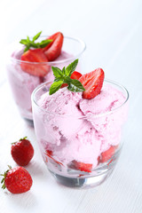 Ice cream in glasses with strawberries on white wooden backgroun