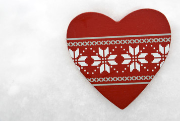 Wooden Christmas heart shaped decoration in snow.