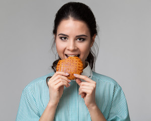 Portrait of an attractive brunette biting a biscuit