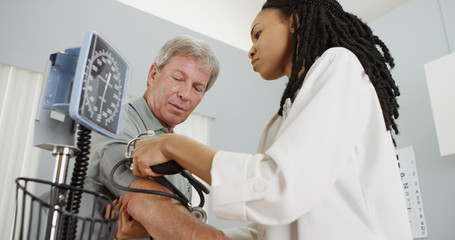 African woman doctor checking patient's blood pressure