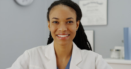 African woman doctor sitting at desk smiling
