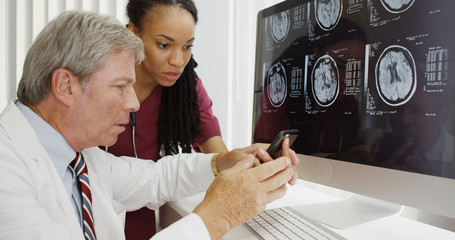 Two doctors analyzing brain xrays on computer