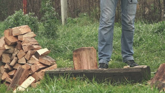 Lumberjack cutting wood logs with axe, man splitting firewood for winter season.
