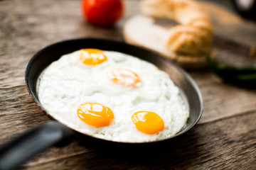 Fried egg in a frying pan on a wooden table