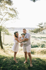 Fototapeta premium Happy family of mother father and lovely daughter in sunset light. 