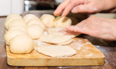 Female hands undress dough on a wooden board for future pies