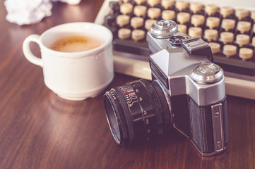 an old typewriter on old wooden table with coffee and old camera