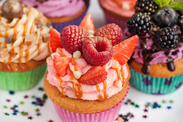 Delicious cupcake decorated with raspberry and strawberry