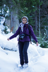 Fototapeta na wymiar Tourist woman with camera in the snowy forest