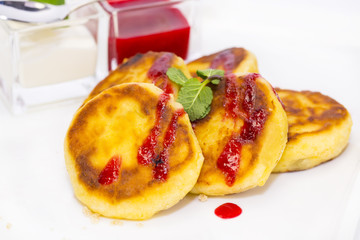 cheesecakes with sour cream and jam on table in restaurant