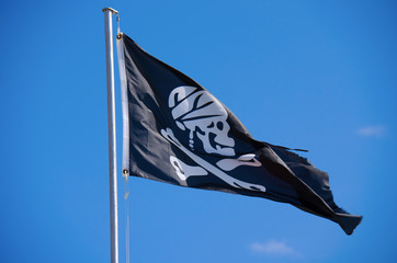 Skull and crossbones Jolly Rogers black flag flying on a flag pole