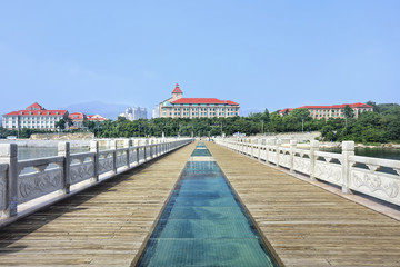 Fototapeta premium Walkway on a pier with stately buildings on the background, Yantai, China