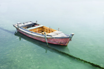 Old weathered wooden boat moored in greenish water.