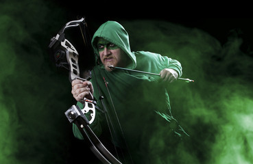 Man in green with mask holding bow and arrow