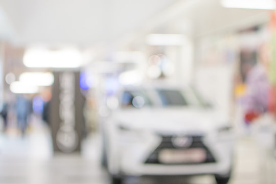 blur image of Commercially cars stand in show room of car shop.