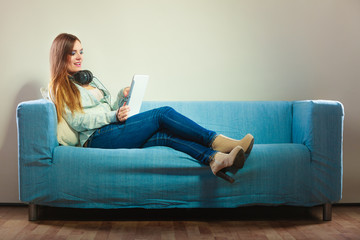 Woman with tablet headphones sitting on couch