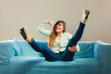 Fashionable girl wearing denim sitting on couch.
