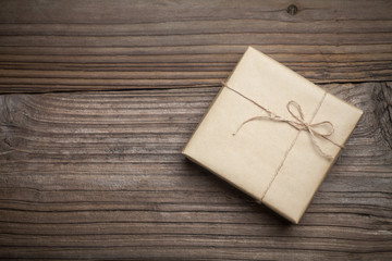 Gift box with brown paper on wood background