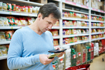 Man with dollars and calculator considers costs in store