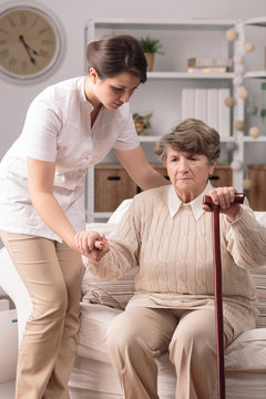 Carer helping senior with stick