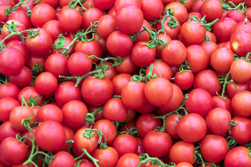 Many red tomatoes at farmers market stall.