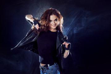 young beautiful girl in a leather jacket on the texture  background, rock style