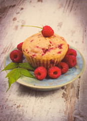 Vintage photo, Fresh baked cupcake and raspberries on plate on old wooden background, delicious dessert