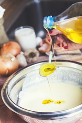Vegetable oil poured from bottle in spoon and bowl