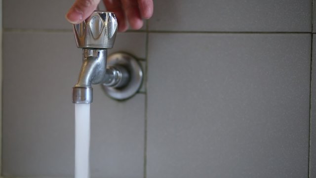 hand opening the tap water potable