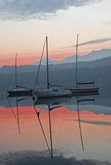 le barche riflesse sull'acqua del lago ,alla luce del tramonto