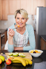 mature woman eating fruit salad at home