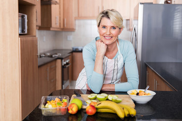 middle aged woman leaning against the kitchen counter