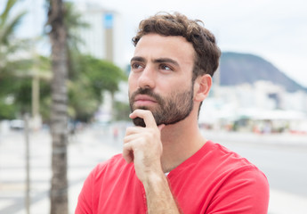Fototapeta premium Nachdenklicher Mann mit rotem Shirt in der Stadt