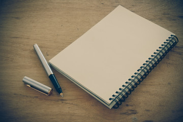 paper notebook and pen on a table with filter effect retro vinta