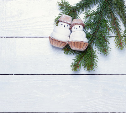 two little funny snowman and fir branch on a wooden surface.view from above.festive background for your design