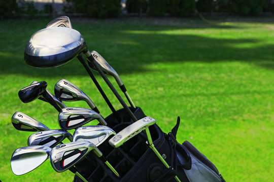 Golf bag with clubs on green field, close up