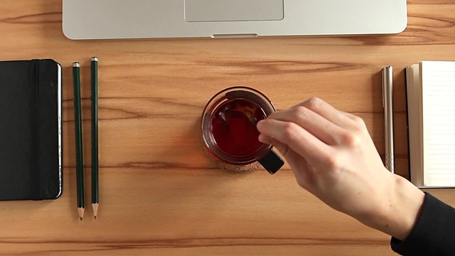 Teel&ouml;ffel Zucker in eine Tasse Tee am Arbeitsplatz einr&uuml;hr