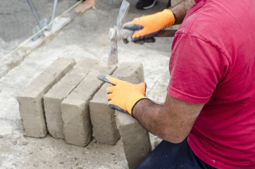 Bricklayer working with mud bricks for building a wall.