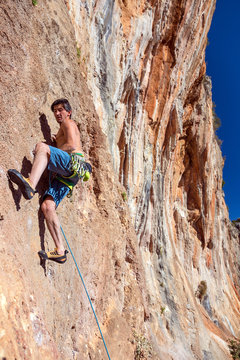 Climber at steep high rocky Wall with gear orange color stone