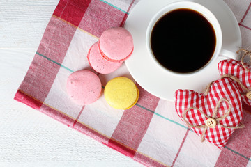 Decorative heart Valentine with a Cup coffee and saucer on a napkin with cakes on wooden background