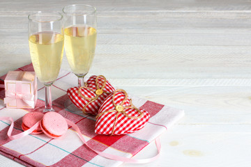 decorative heart with gift and champagne glasses and cake on a napkin on wooden table