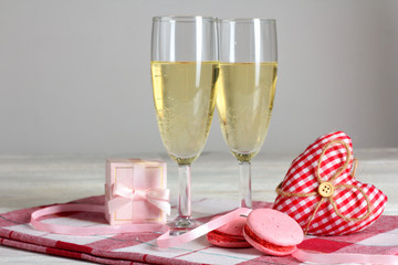 decorative heart with gift and champagne glasses and cake on a napkin on wooden table