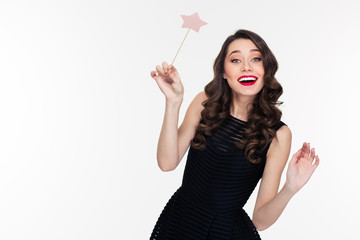 Cheerful beautiful curly young woman posing with magic wand