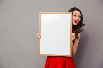 Cheerful woman holding blank board