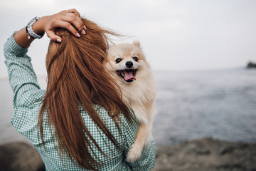 Young woman is holding dog outdoors